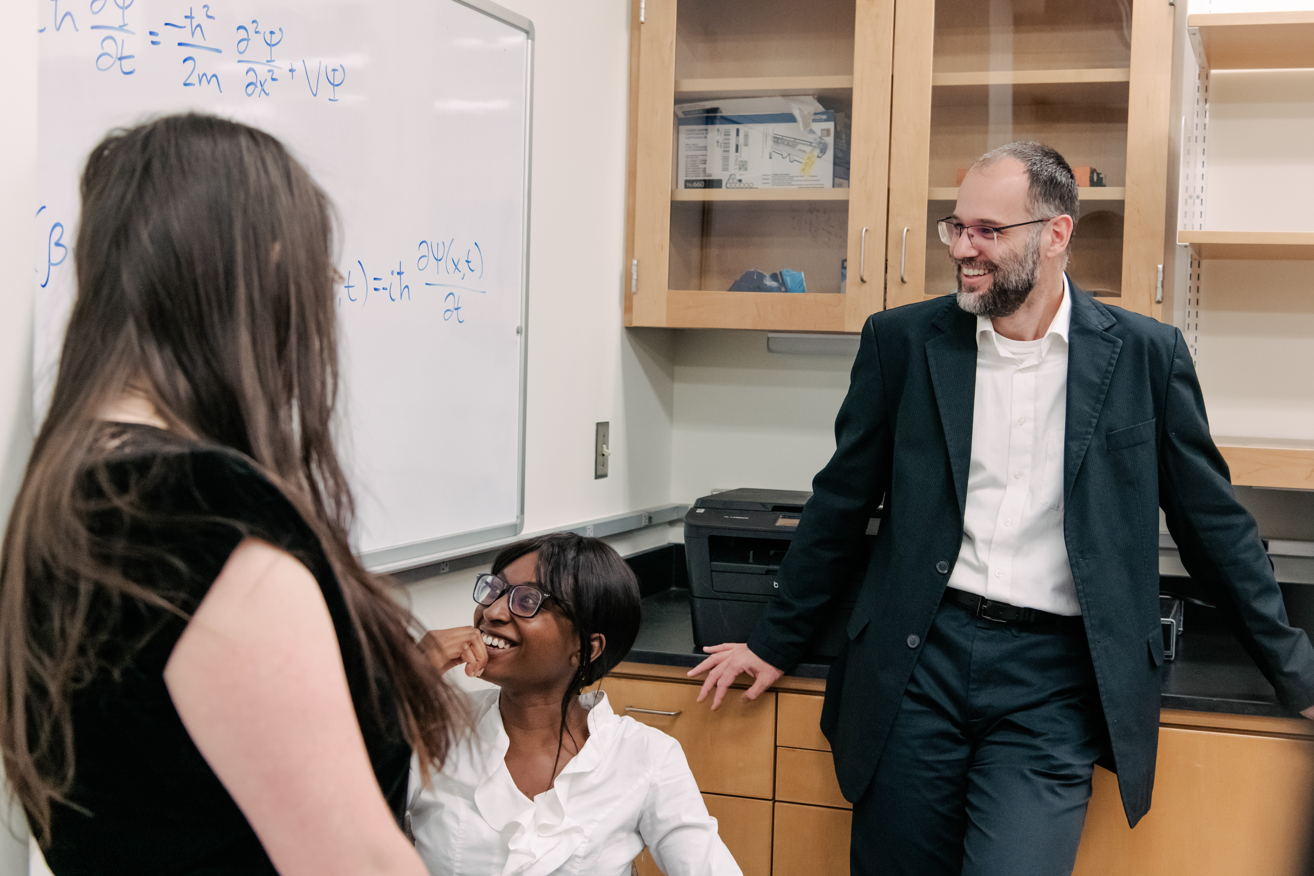 Sebastian Deffner stands with two students, working on a whiteboard with equations