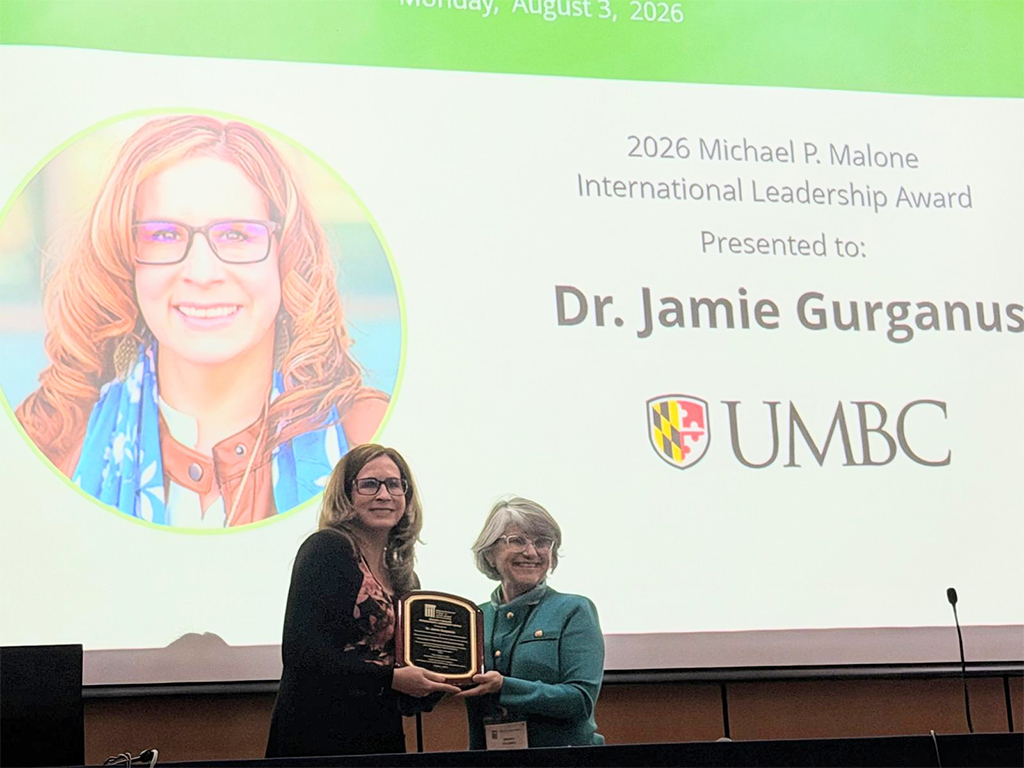 Gurganus accepts plaque on stage at APLU
