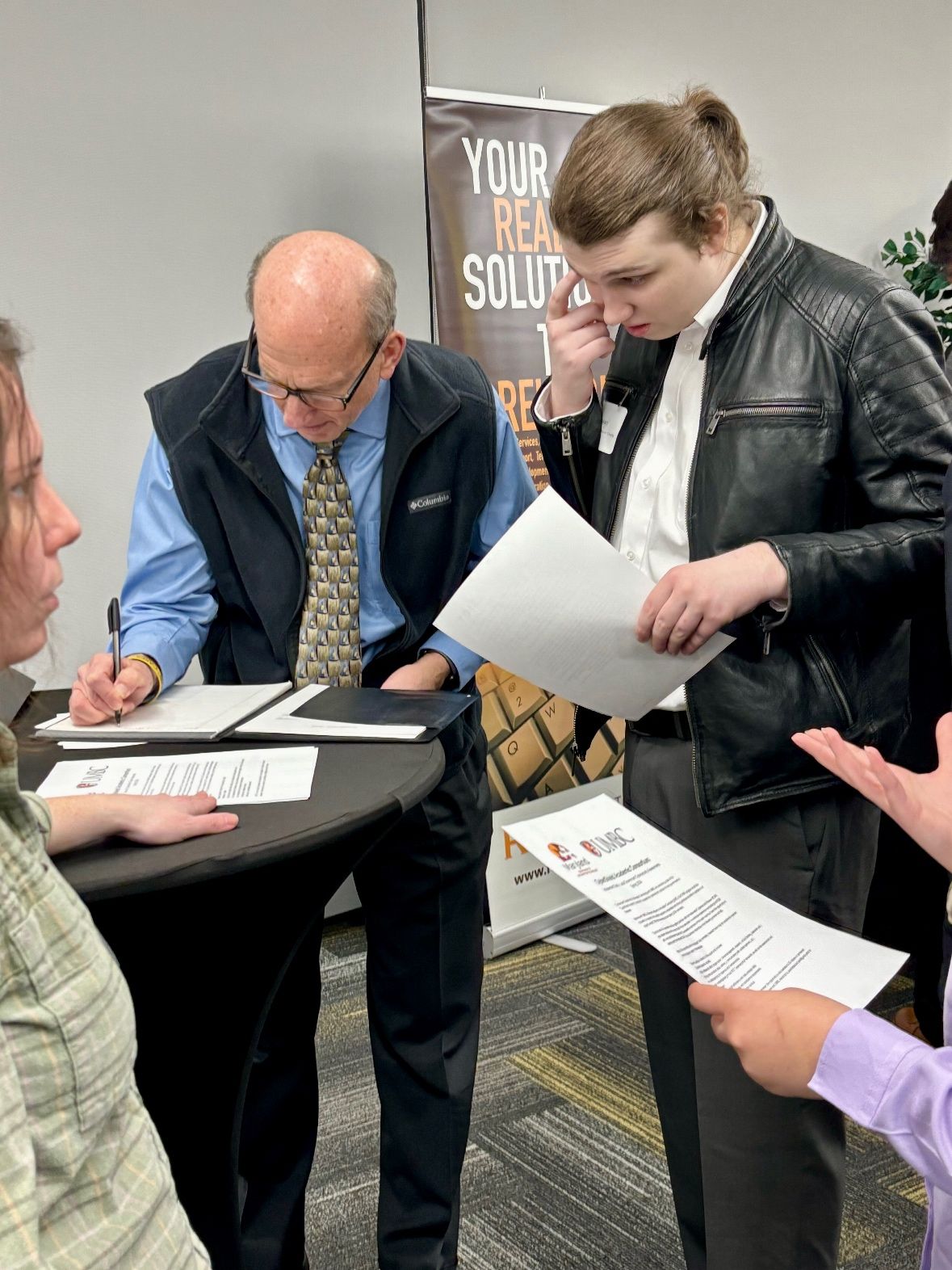 Jack Suess is writing notes when speaking with a student about potential job opportunities.