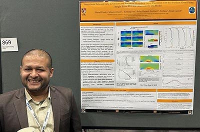 Sharad Pandey smiles and stands next to his poster presentation.