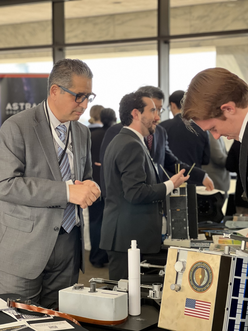 Dr. Benna in grey suit talks with interested staffer about instruments on display.