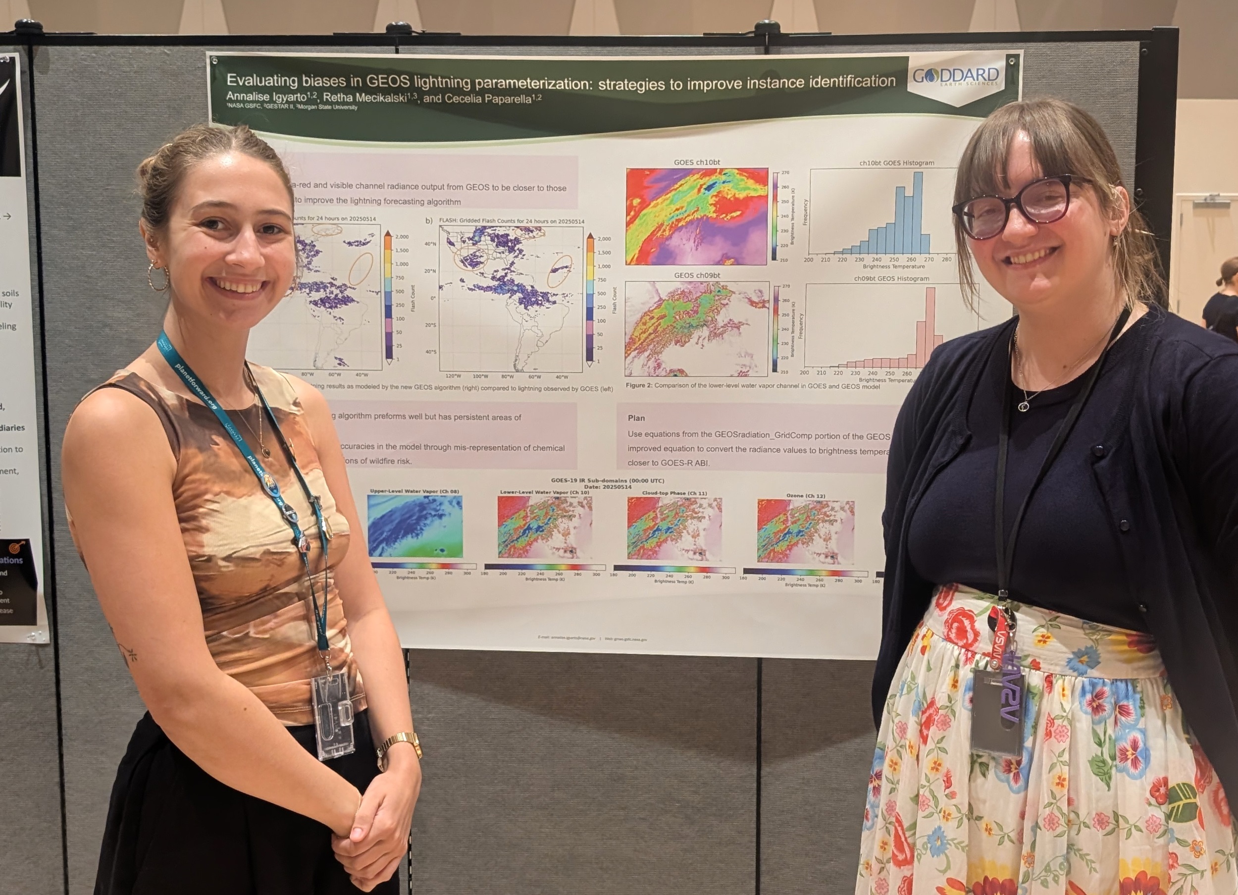 Cecelia and Annalise stand on either side of the poster, both are smiling. Annalise is in a floral skirt and dark sweater, Cecelia - a bronze colored top and dark skirt.