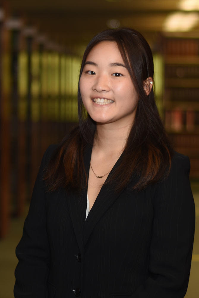Anna wearing a black blazer and smiling.