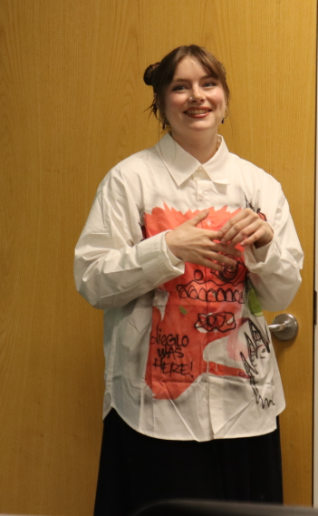 Chloe smiling in a white collared shirt with red art