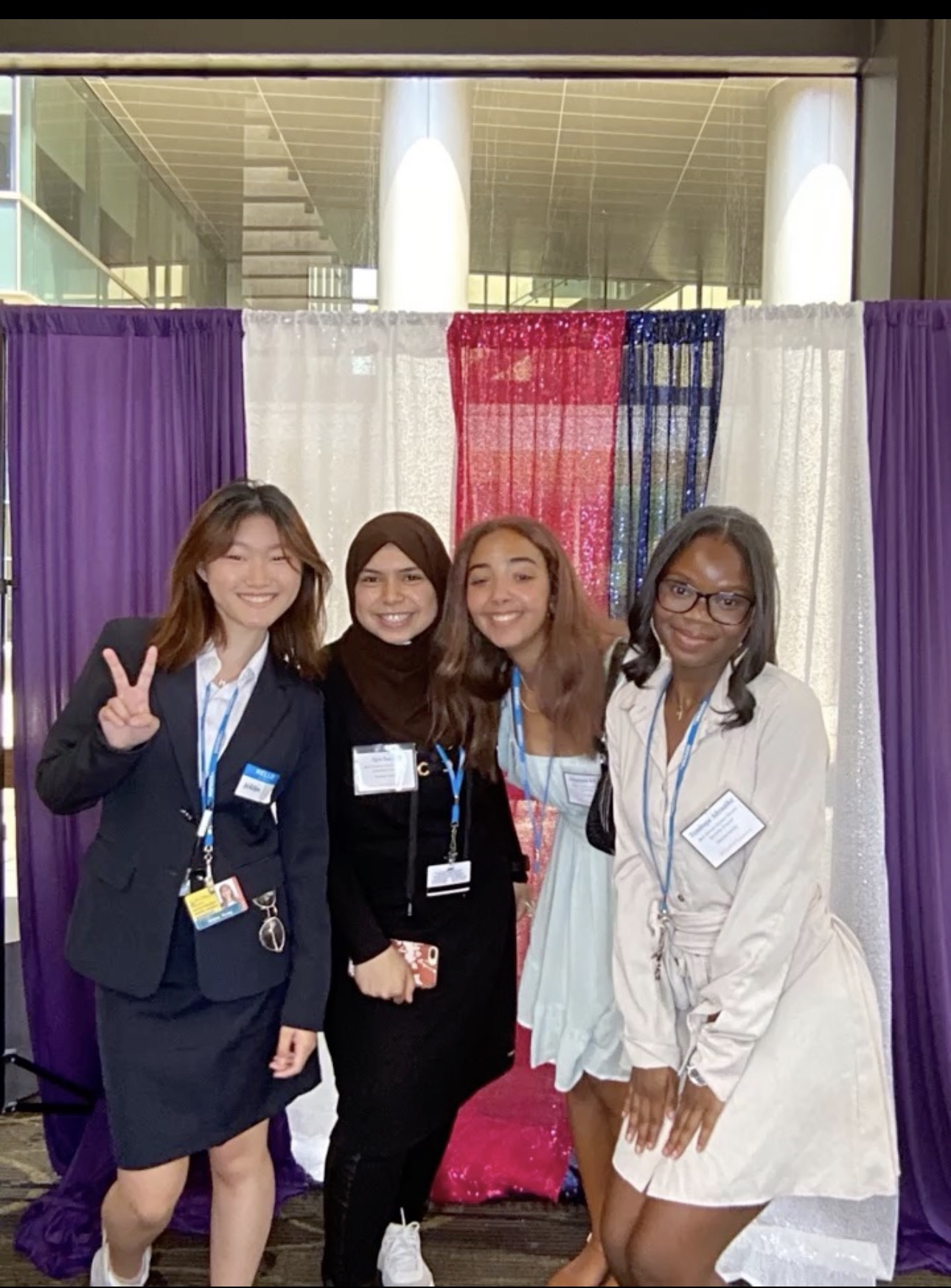 Aya standing next to a group of women with a multi-colored backdrop behind them smiling