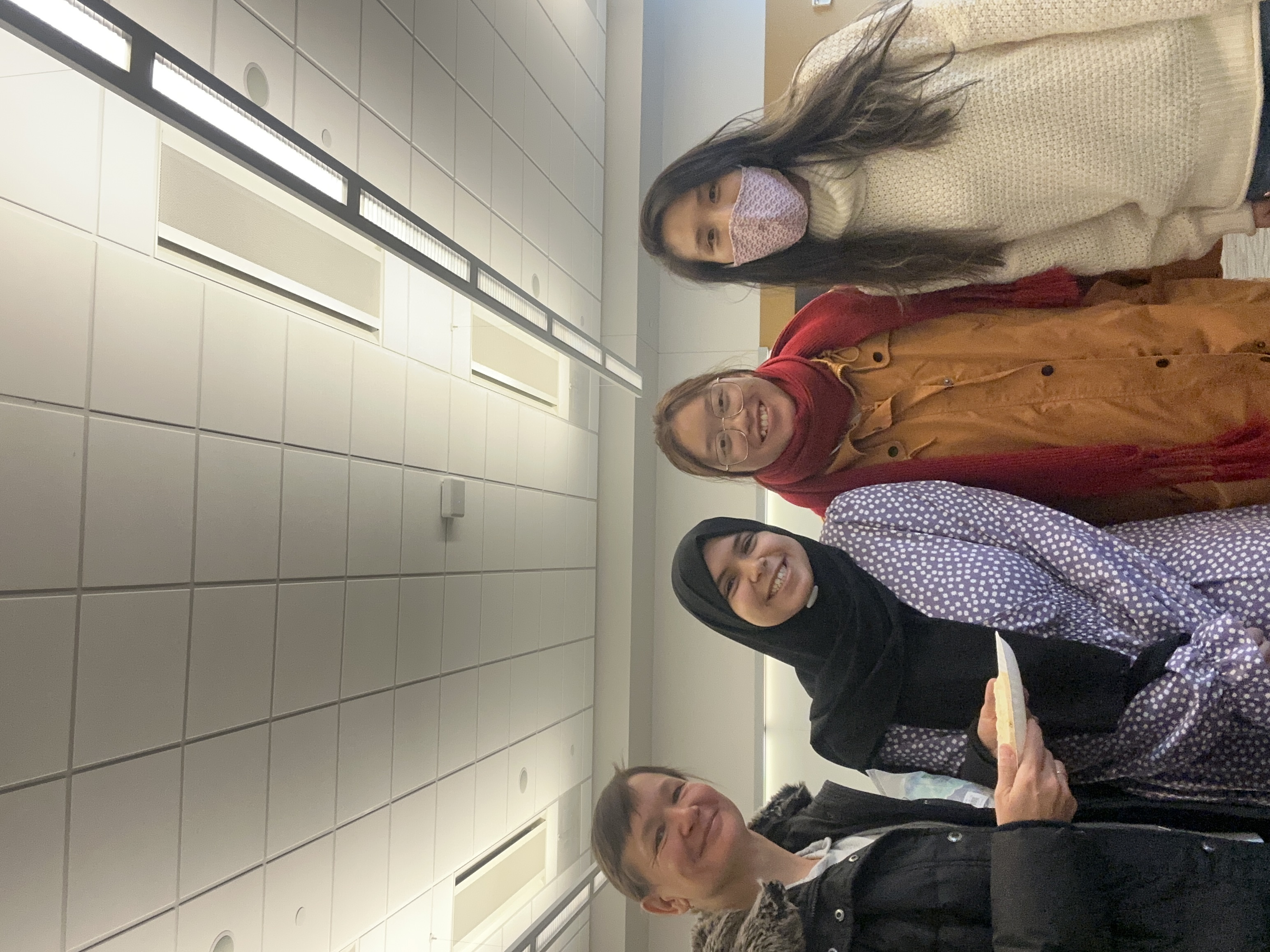 Aya standing with a group of students smiling inside of a classroom