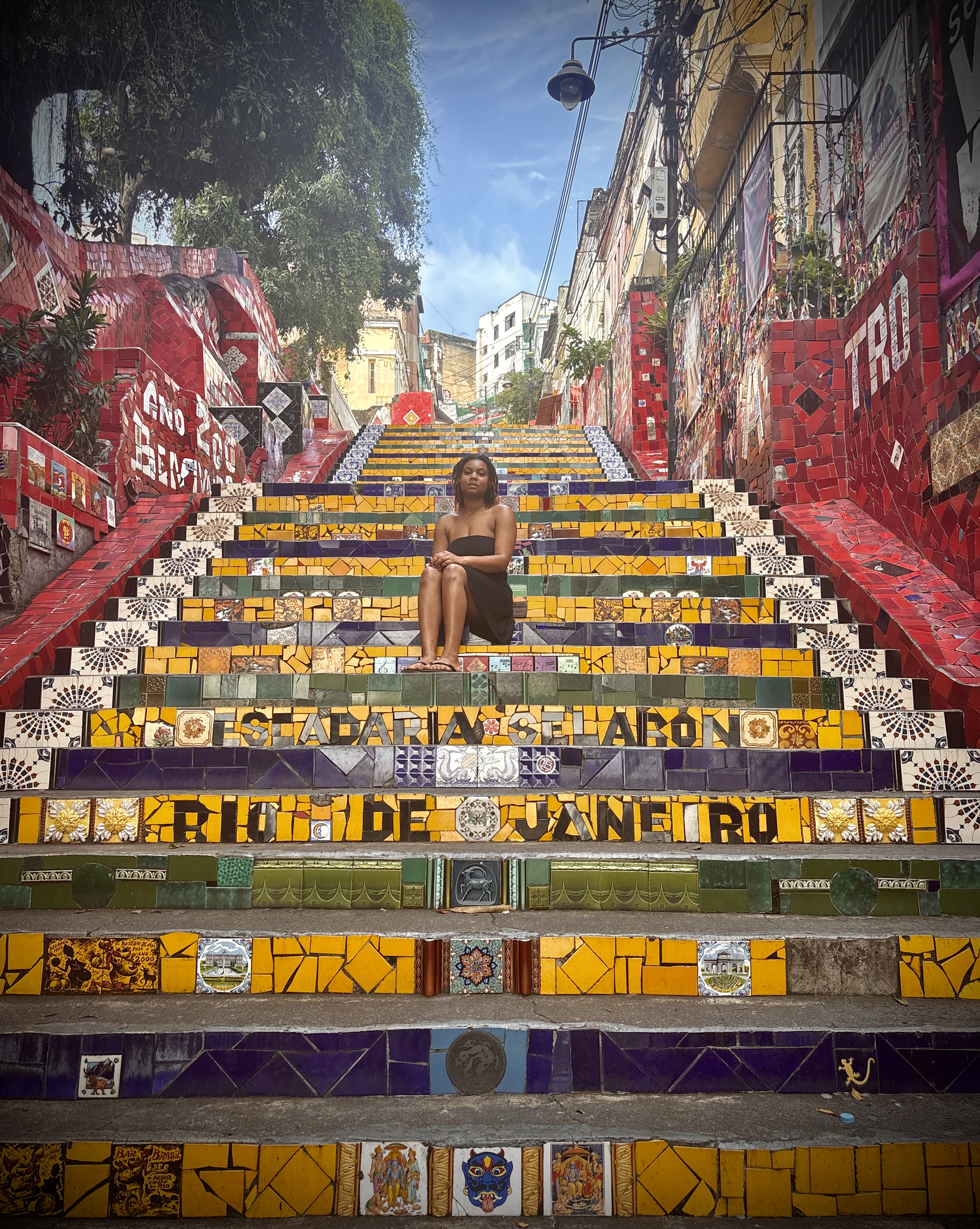 Shania siting on colorful steps with wording "Rio de Janeiro" with buildings in the background