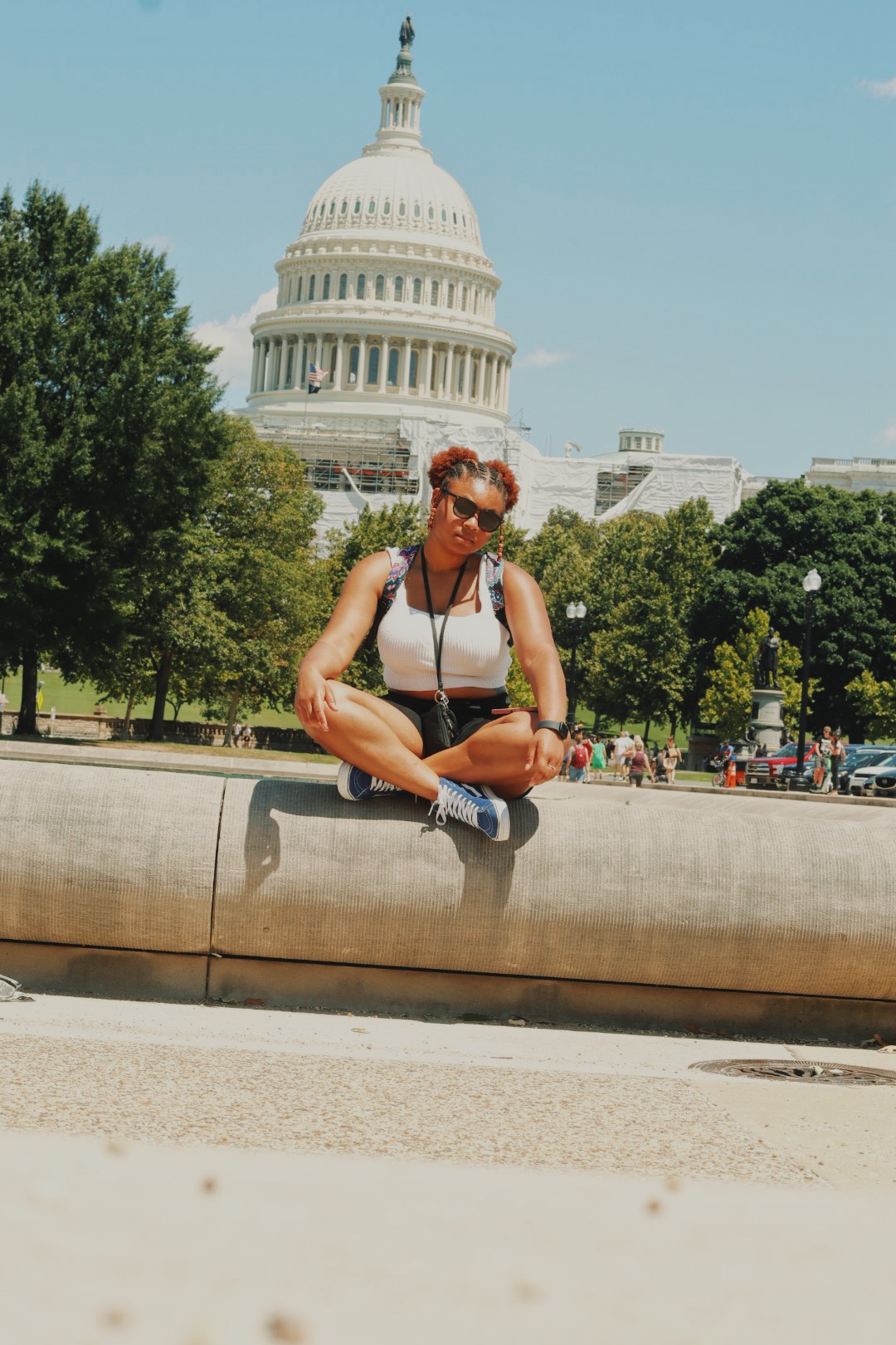 Shania siting on wall with legs cross with white building behind