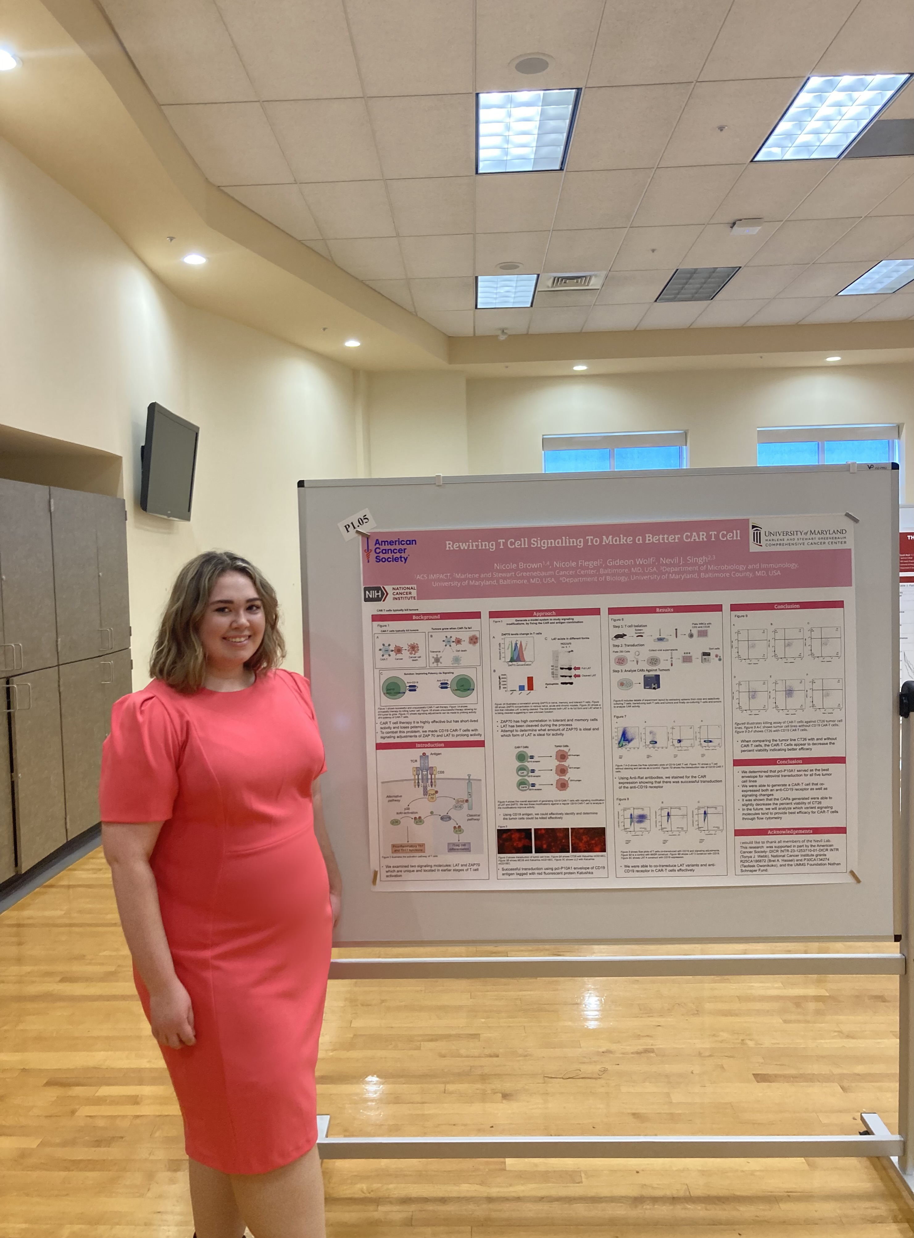 Nicole in a pink dress smiling next to research on a poster board