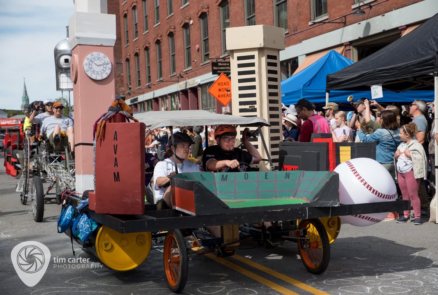 The Image Man as Charm City Bromobile. It includes the Baltimore Inner Harbor World Trade Center, Camden Yards stadium, the American Visionary Art Museum (AVAM), and Bromo-Seltzer tower.