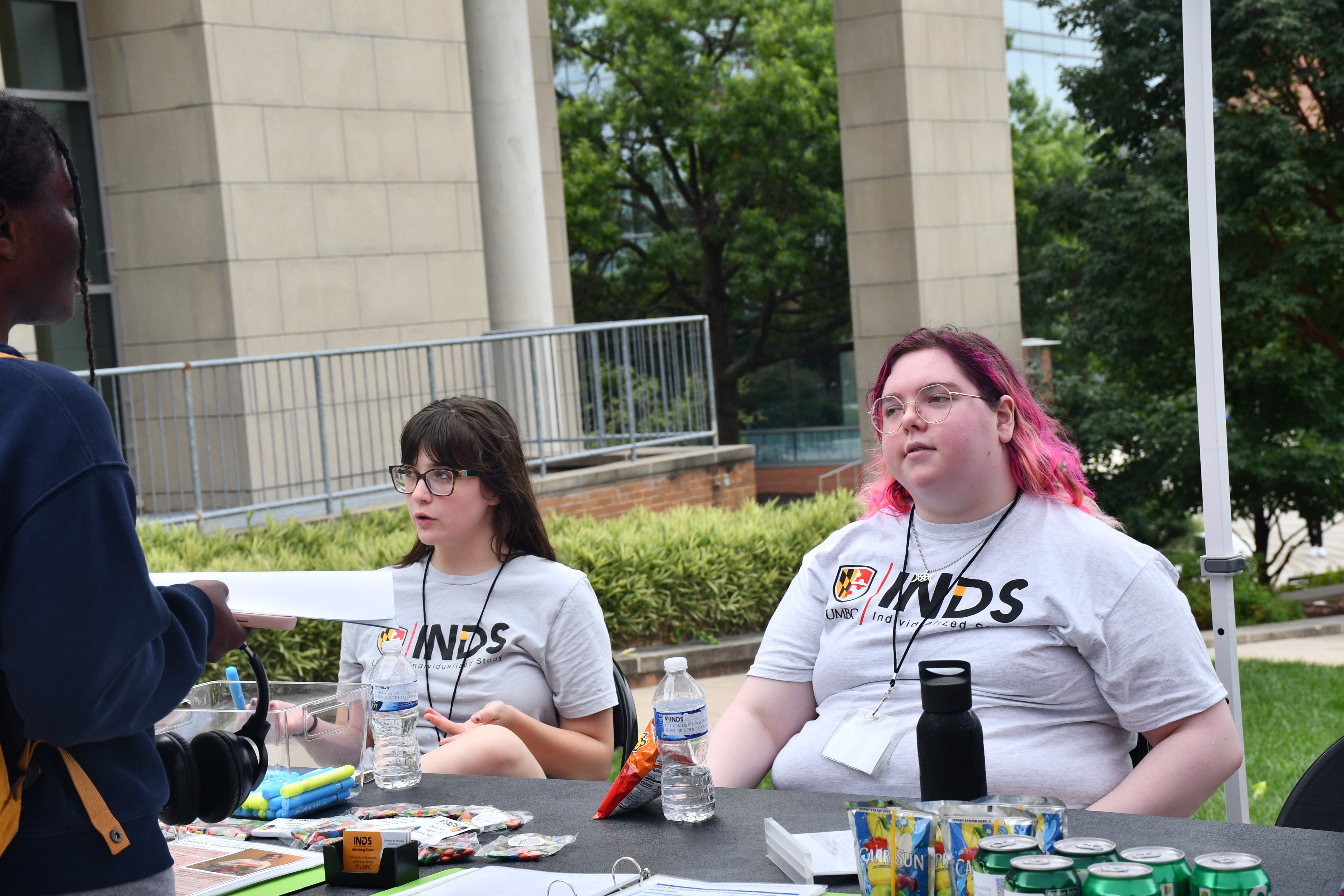 Sofia siting at table with fellow classmate talking to a student who approached the table to discuss INDS