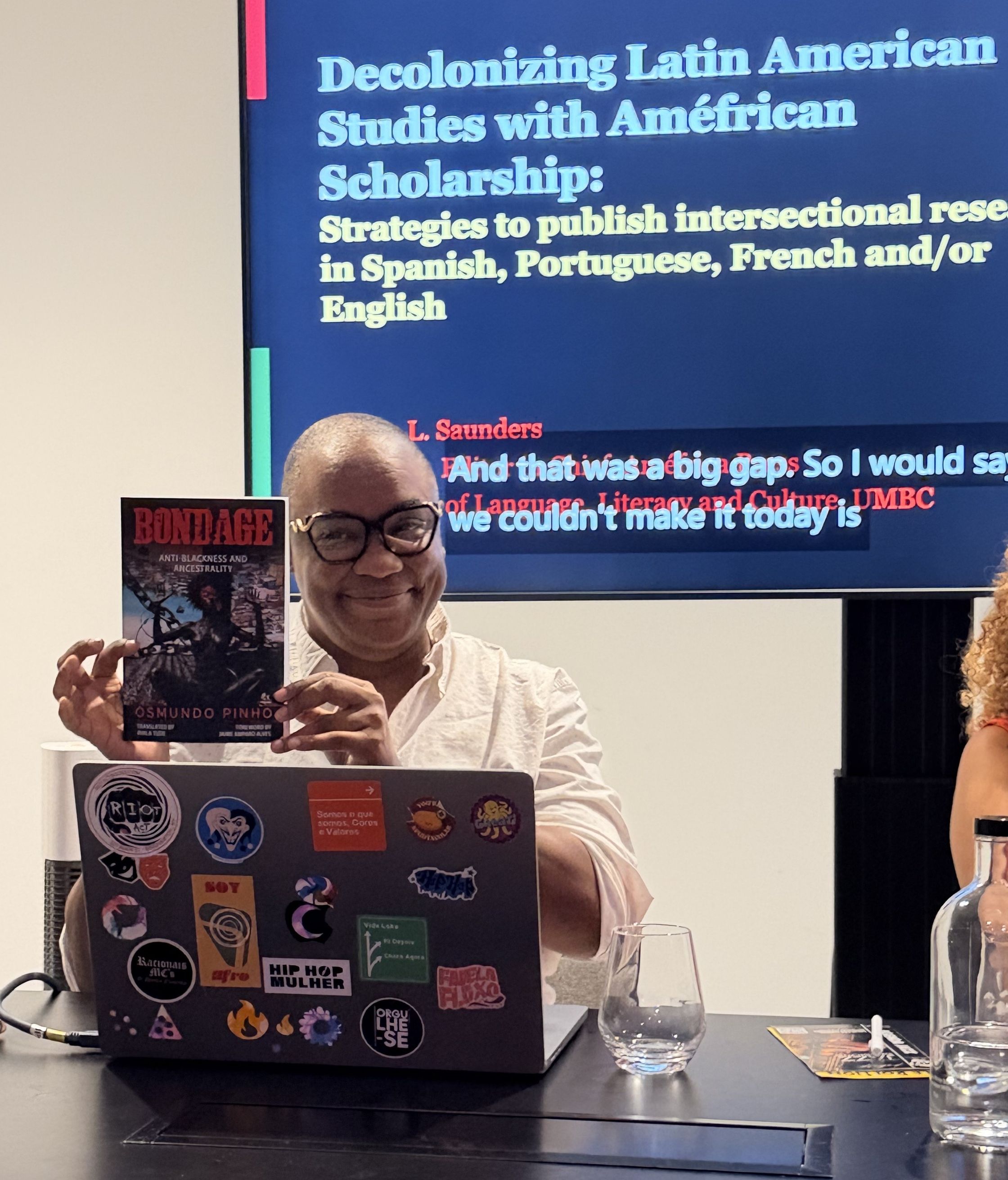 Black person holding book with laptop in front of them.