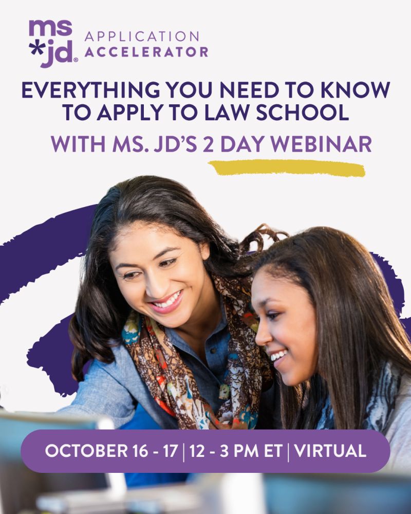 Two women, each with long brown hair and smiling, seated next to each other looking at laptop