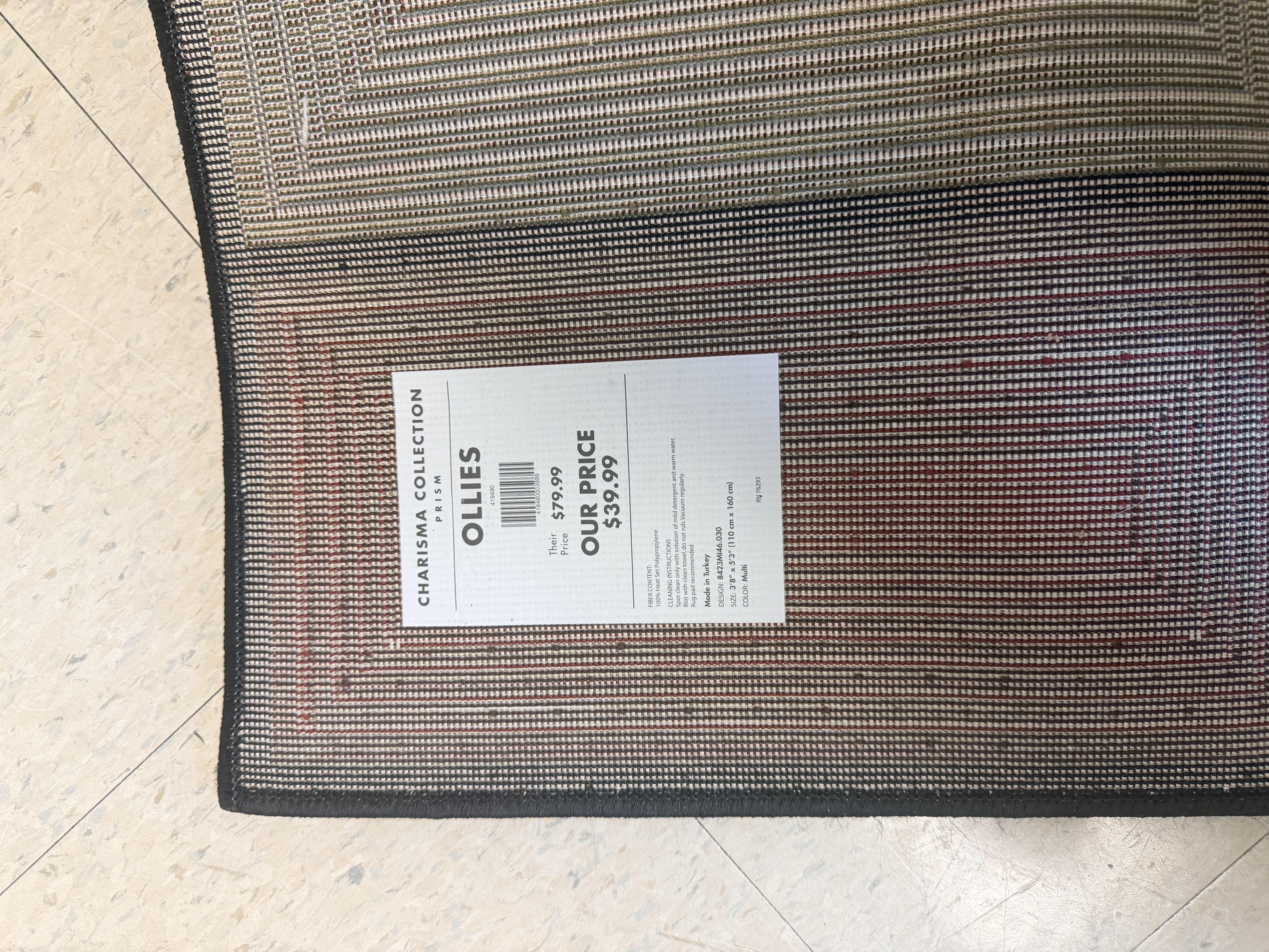 Photo of tag on the back of a multicolored carpet Reads Ollies 3'8" X 5'"