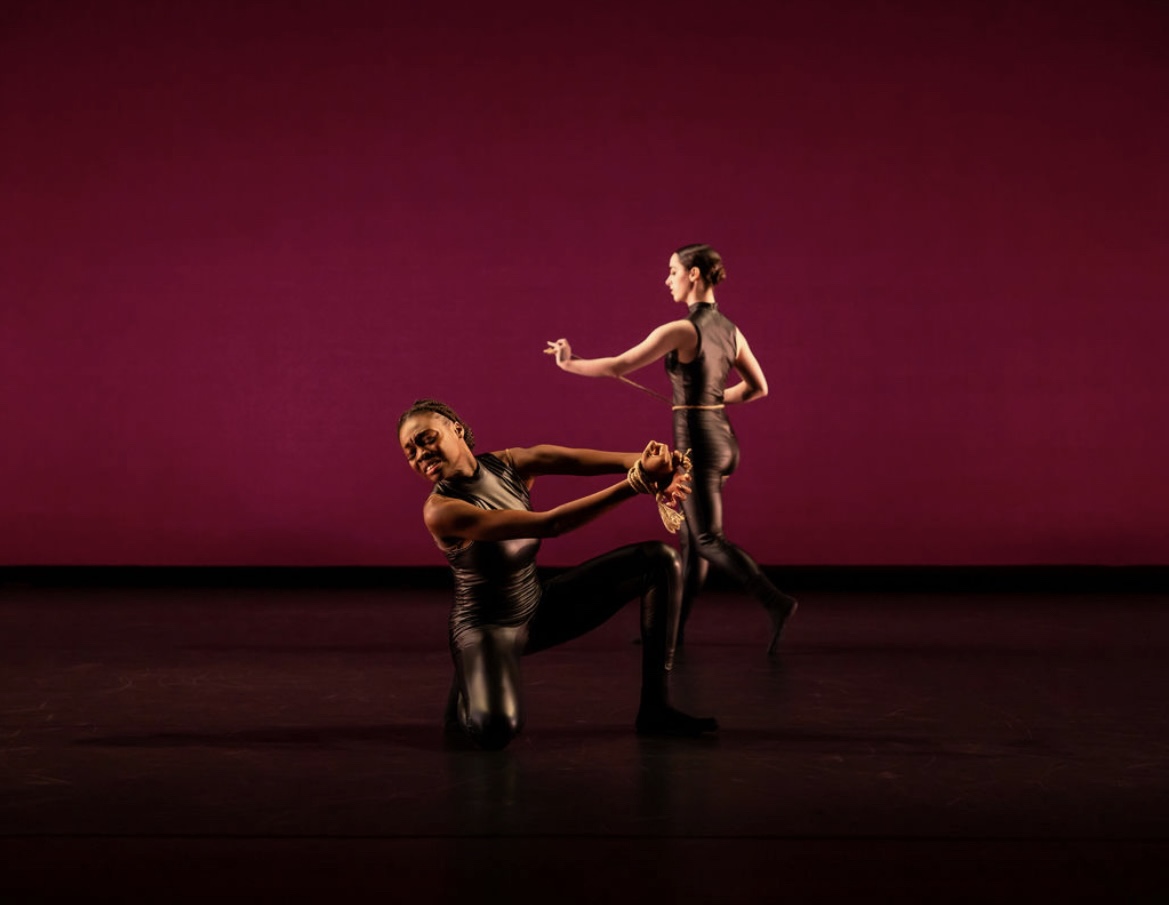Joanna on stage with another dancer performing with a red background