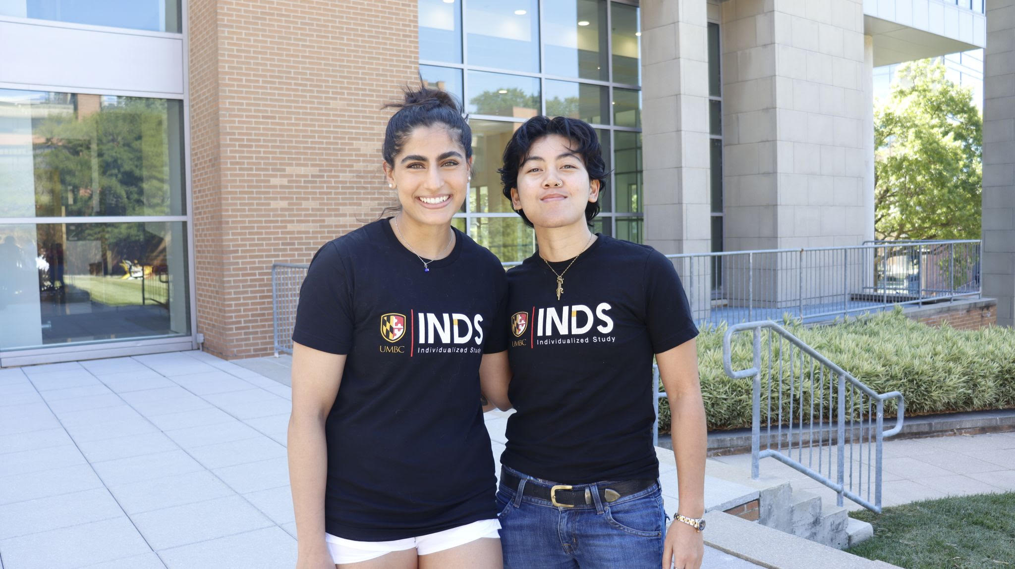 Shreya and Thalia wearing their UMBC INDS shirts and smiling.