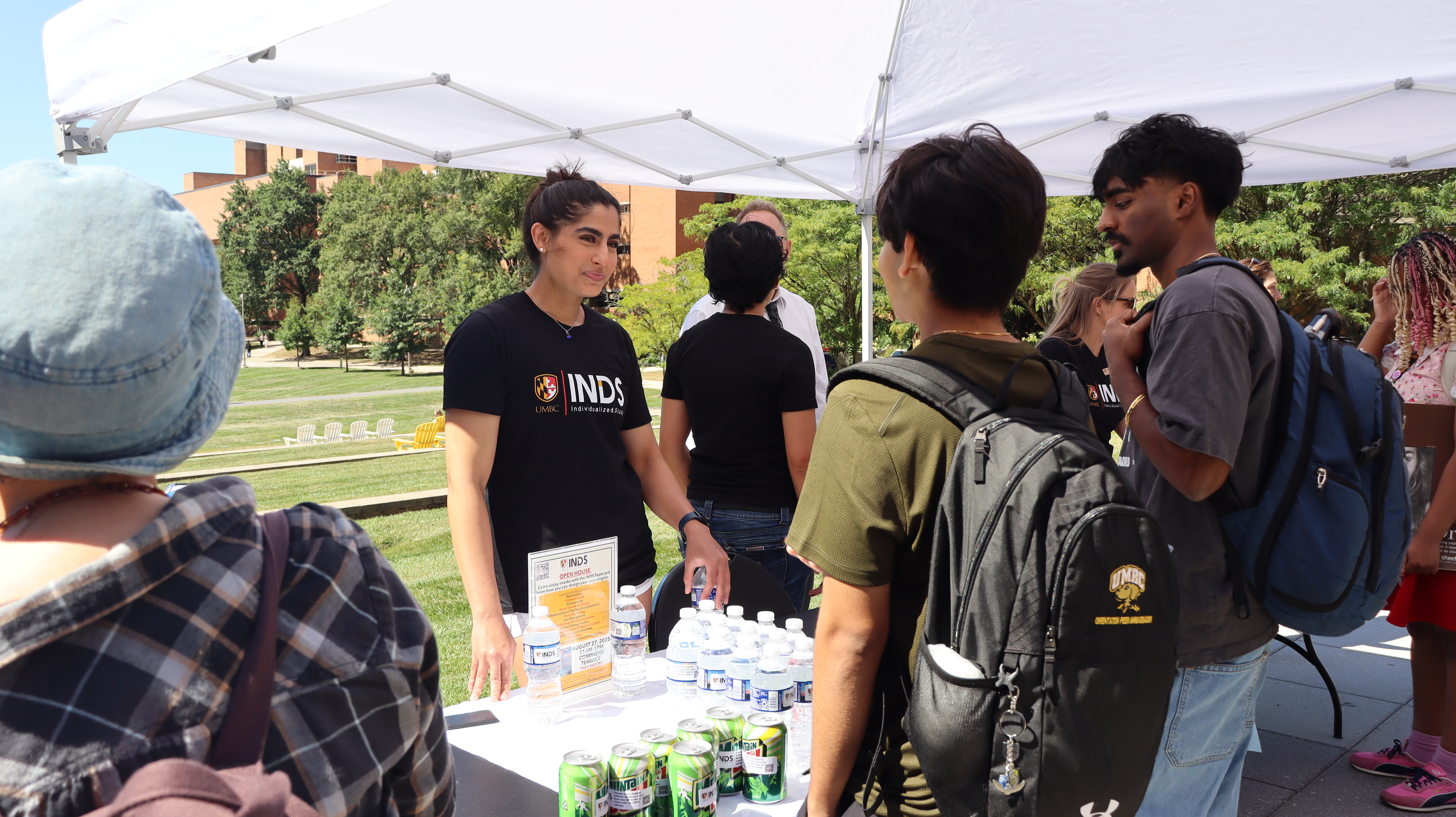 Shreya in black t-shirt with INDS logo talking to students at the INDS welcome week event