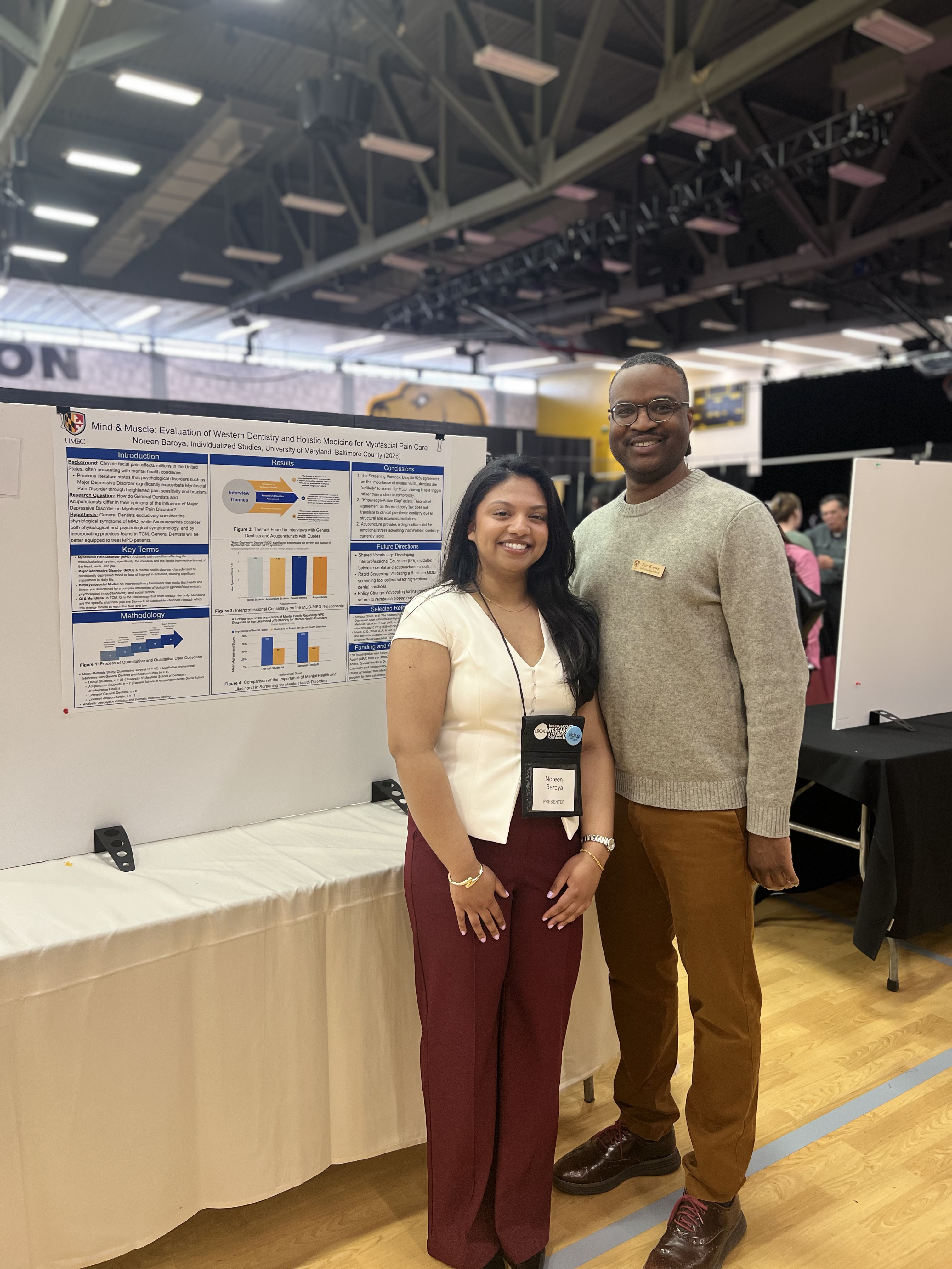 Noreen standing next to Professor Brown with research poster board in the background, smiling