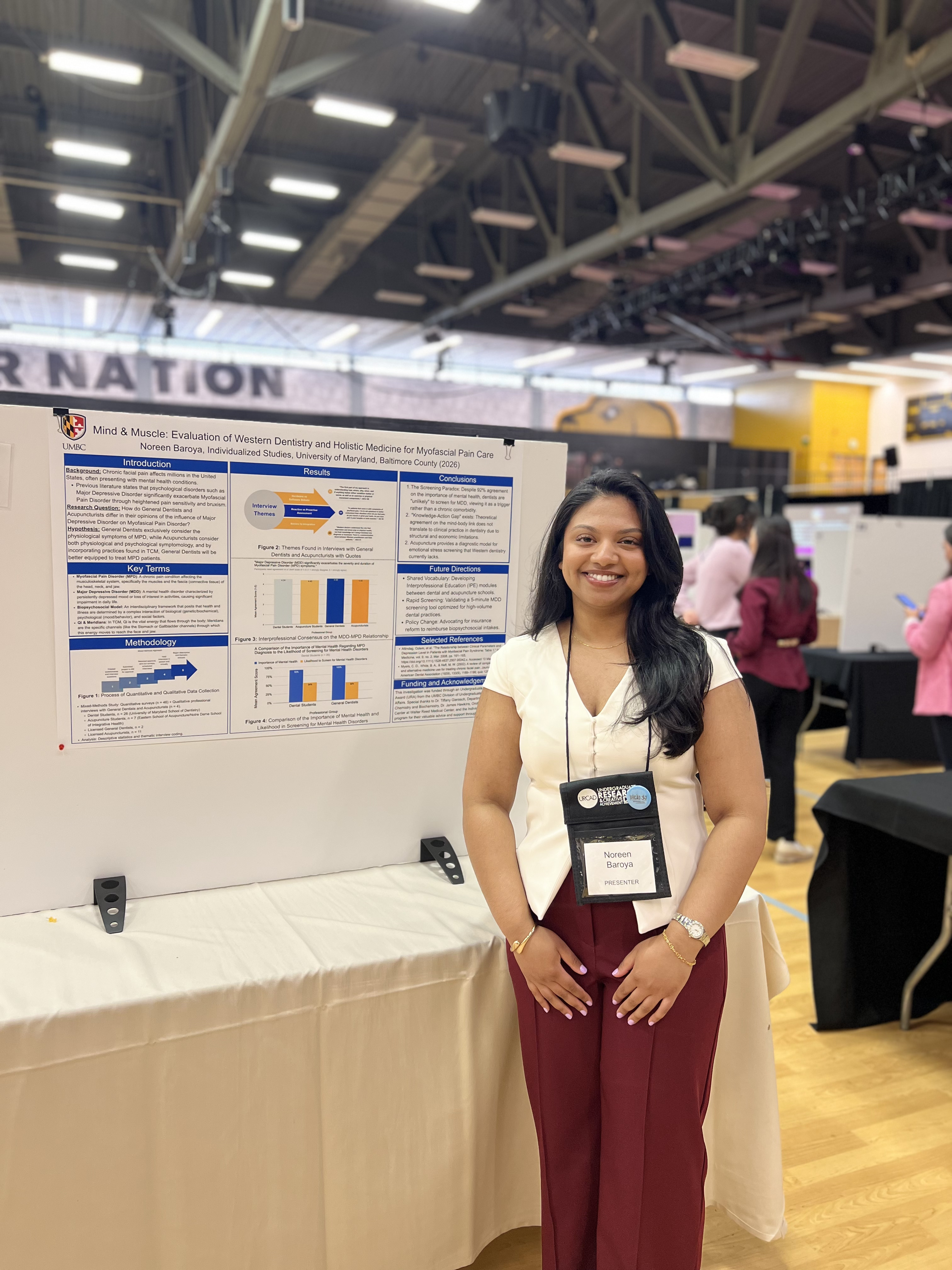 Noreen smiling standing next to research poster board