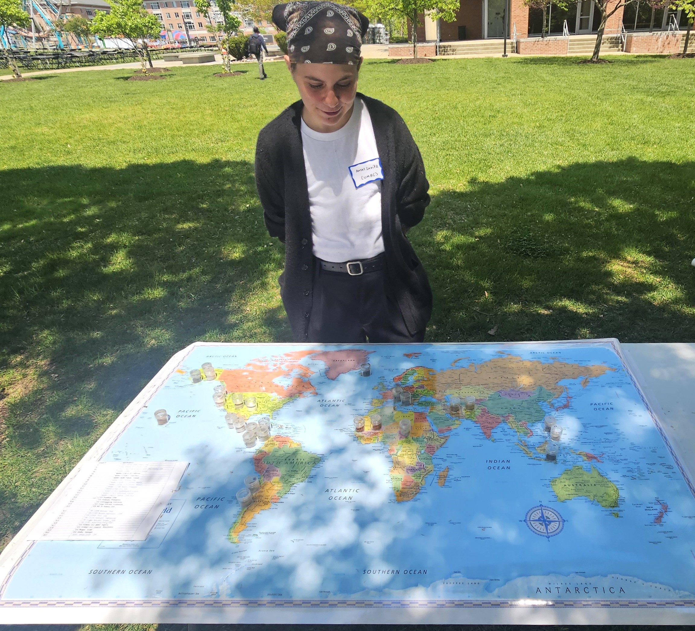 Ansel stands behind world map with small containers of dust and ash placed from their source.