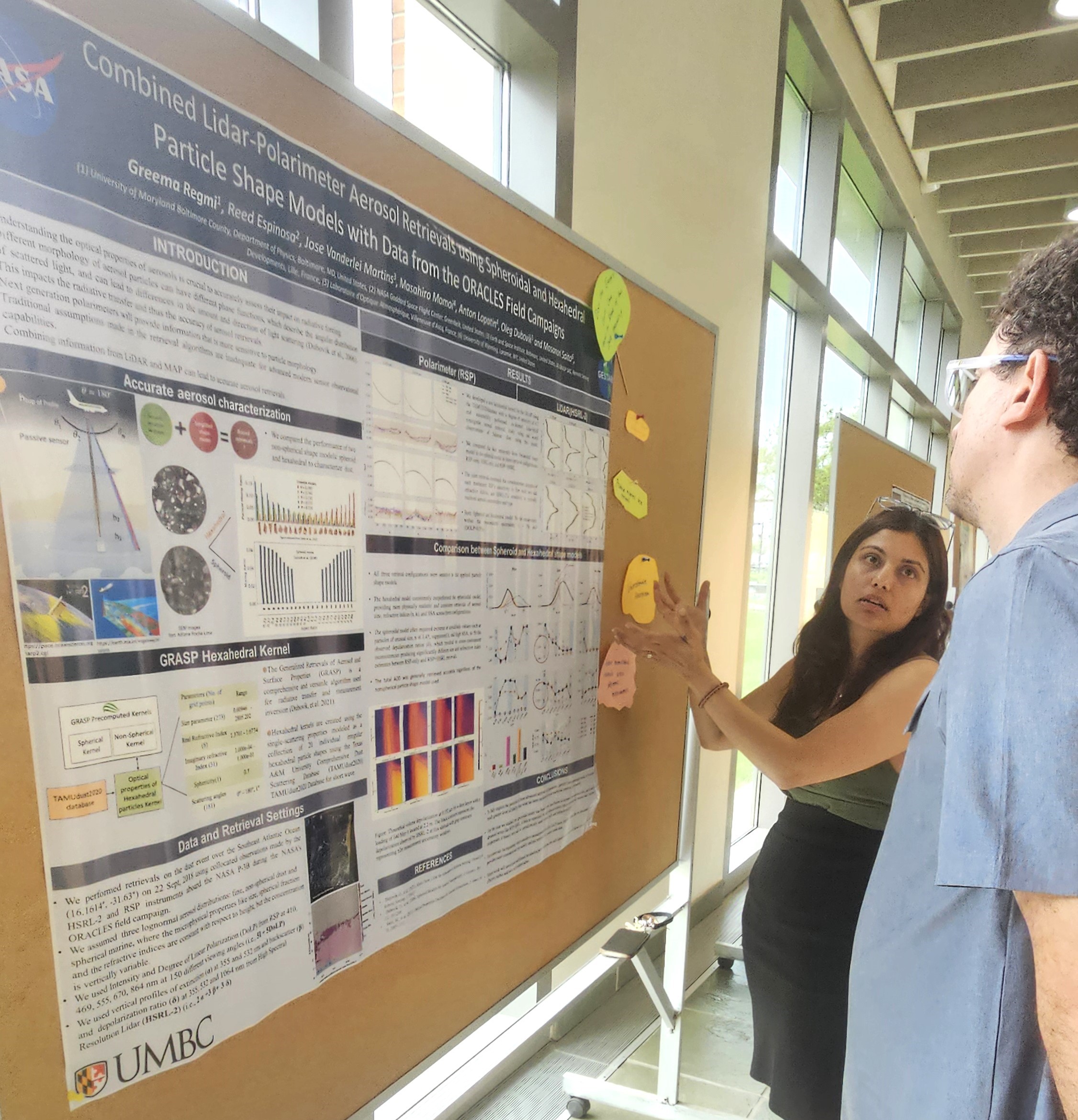 Greema talks with an attendee about her research poster in the Physics hallway.
