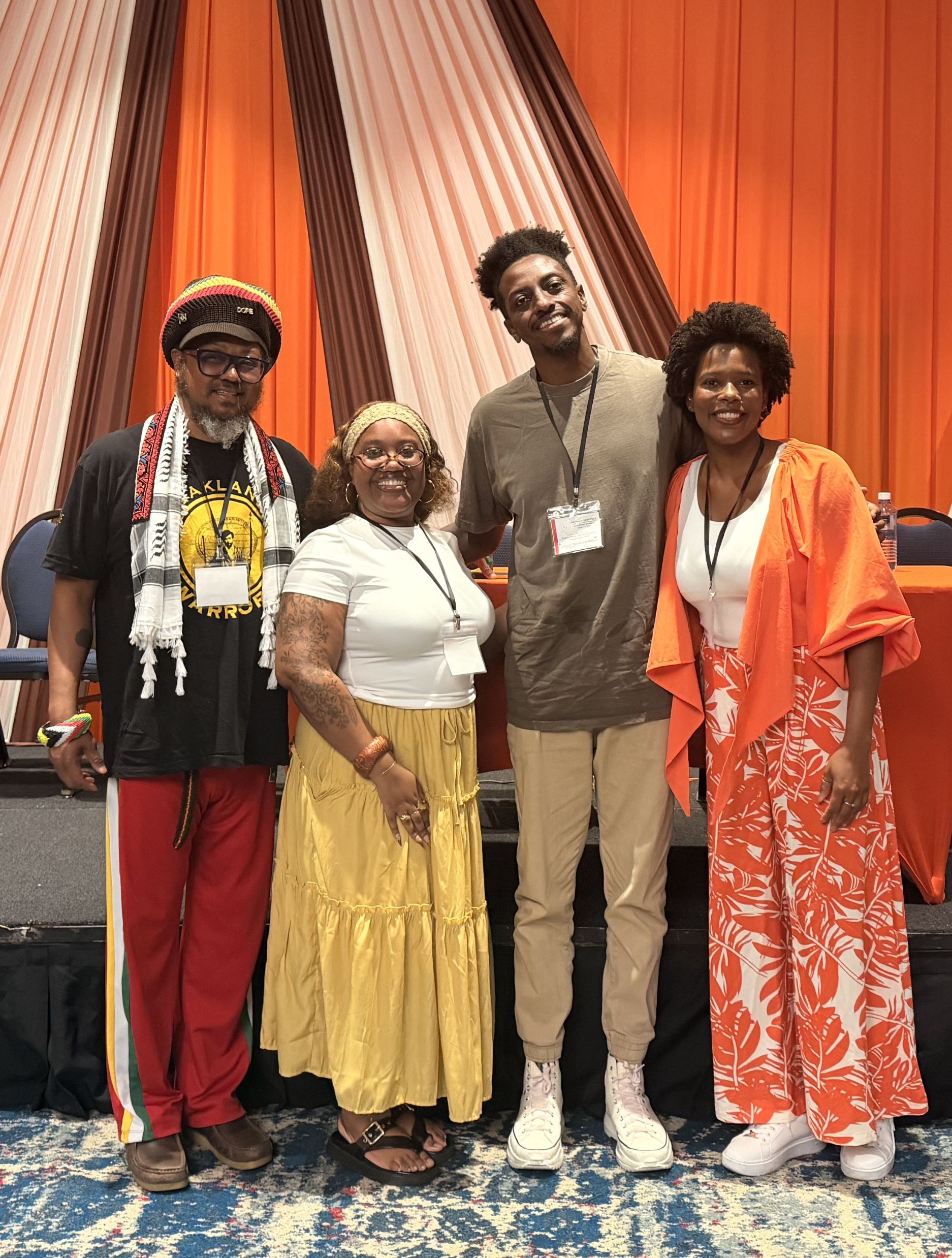 Group of four black people standing, smiling.