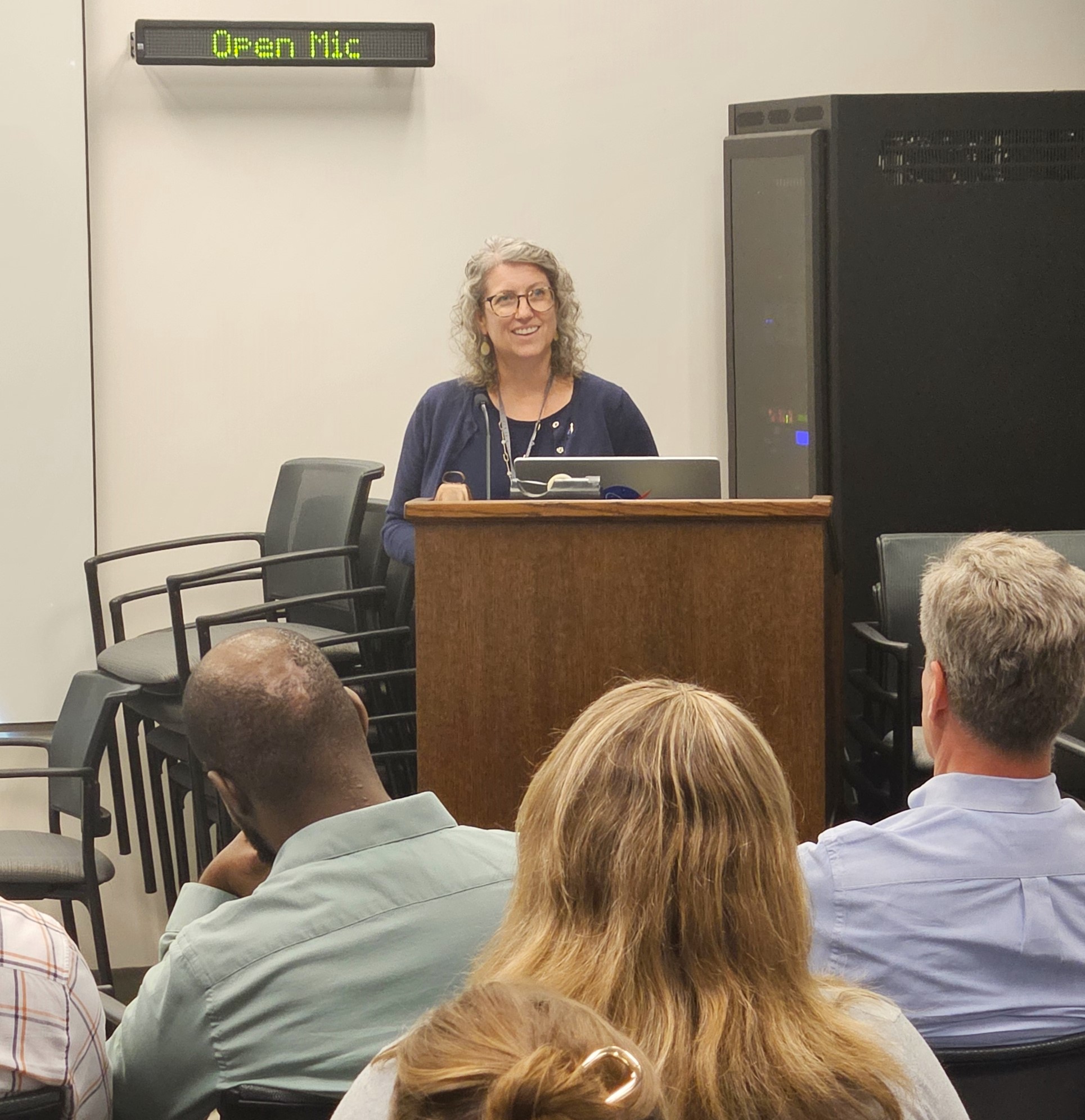 Dr. Stephanie Getty stand at a podium and welcomes the attendees to the event.
