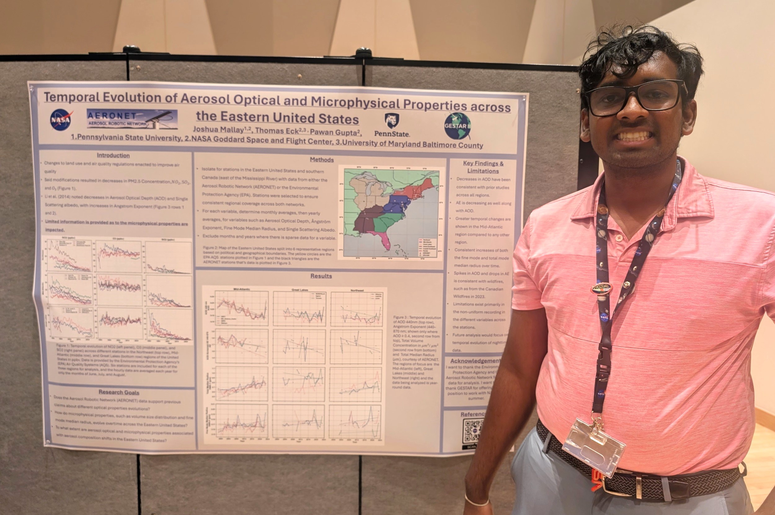 Joshua Mallay stands to the left of his poster in a pink polo.